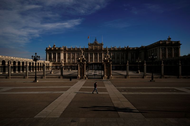 &copy; Reuters. Un hombre habla por teléfono mientras cruza por delante del Palacio Real de Madrid
