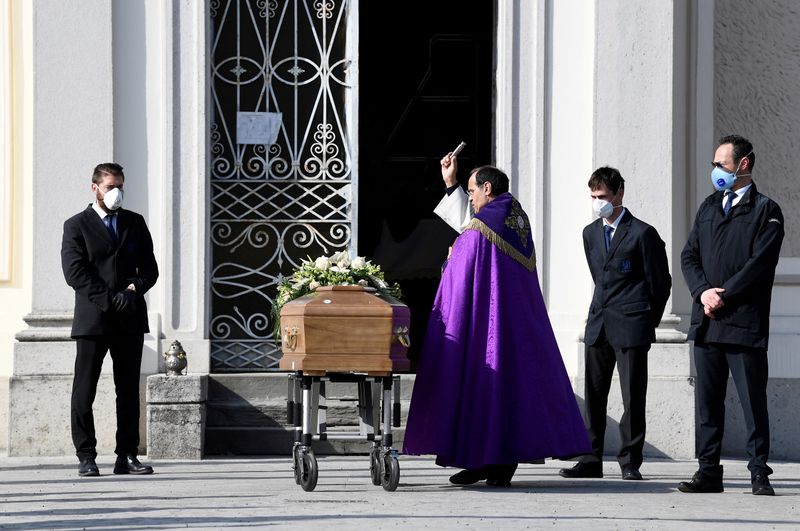 &copy; Reuters. FOTO DE ARCHIVO: Un sacerdote bendice el ataúd de una mujer que murió por causa del coronavirus en Seriate
