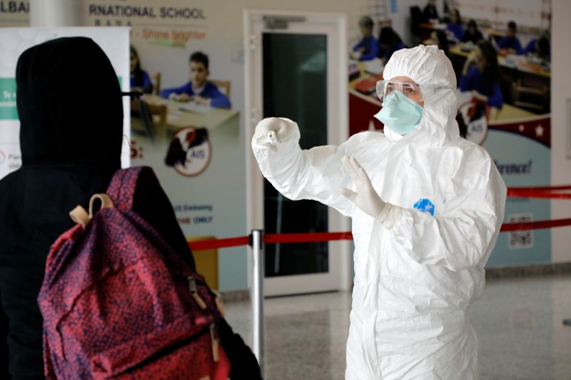 &copy; Reuters. Medical staff member, wearing protective suit, gestures at Tirana International Airport