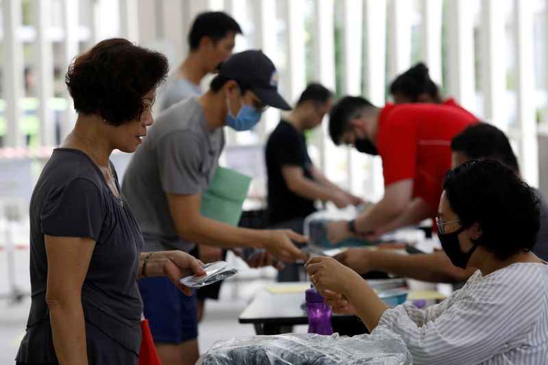 &copy; Reuters. Varios ciudadanos reciben mascarillas reutilizables gratuitas distribuidas por el Gobierno de Singapur en un centro comunitario