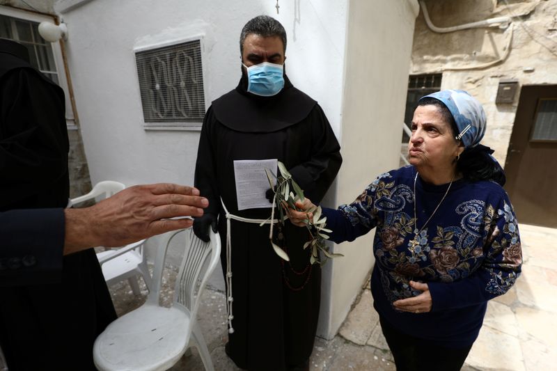 &copy; Reuters. رهبان يقدمون أغصان الزيتون للمسيحيين في القدس الخالية من المارة في أحد السعف