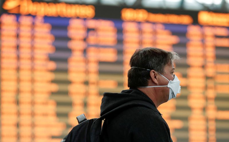 &copy; Reuters. Un uomo con una maschera protettiva presso l&apos;aeroporto di Roma Fiumicino