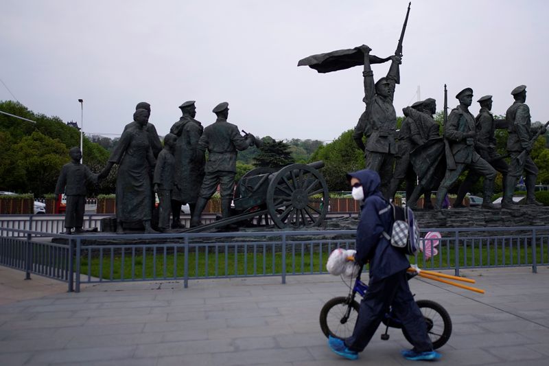 &copy; Reuters. Morador com máscara de proteção passa por praça de Wuhan, na província chinesa de Hubei