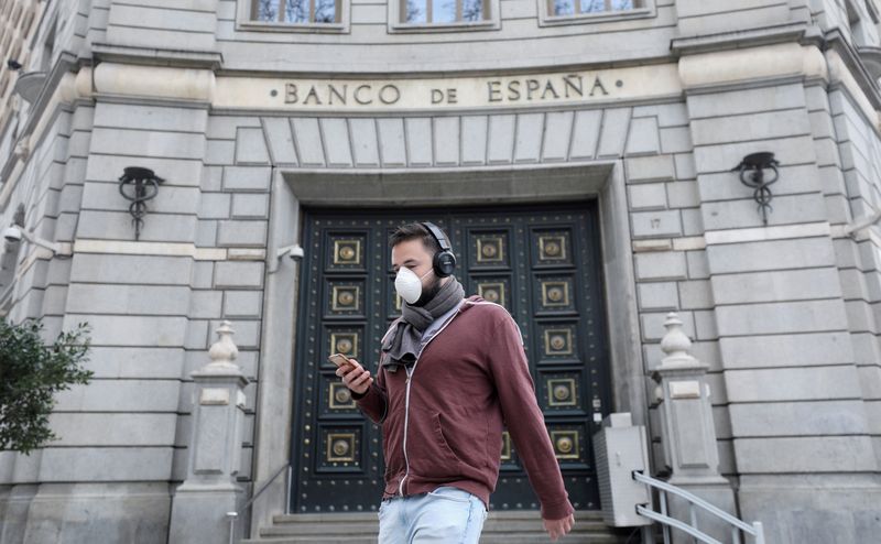 © Reuters. FILE PHOTO: A man wears a protective face mask as he walks past Banco de Espana (Bank of Spain), amidst concerns over coronavirus outbreak, in Barcelona