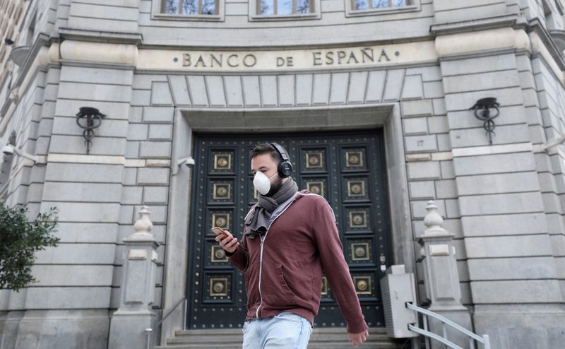 &copy; Reuters. FOTO DE ARCHIVO: Un hombre con una mascarilla pasa junto a unas oficinas del Banco de España, en Barcelona