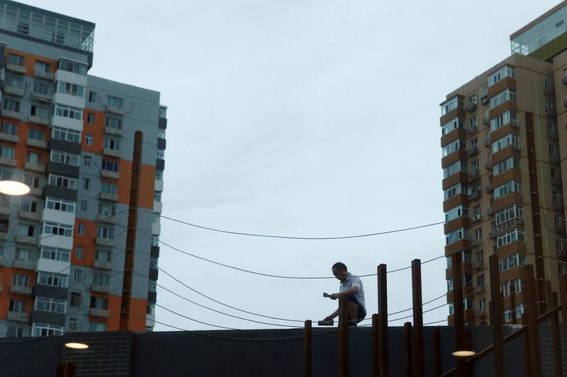 &copy; Reuters. Man works on renovating an office building near residential buildings in Beijing