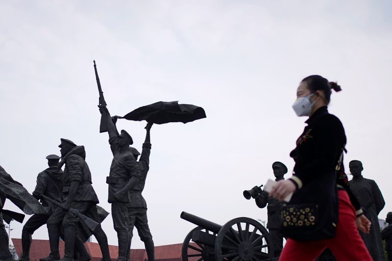 &copy; Reuters. A resident wearing a face mask walks past statue symbolising Xinhai Revolution, a revolution that toppled China&apos;s last emperor in 1911, in Wuhan