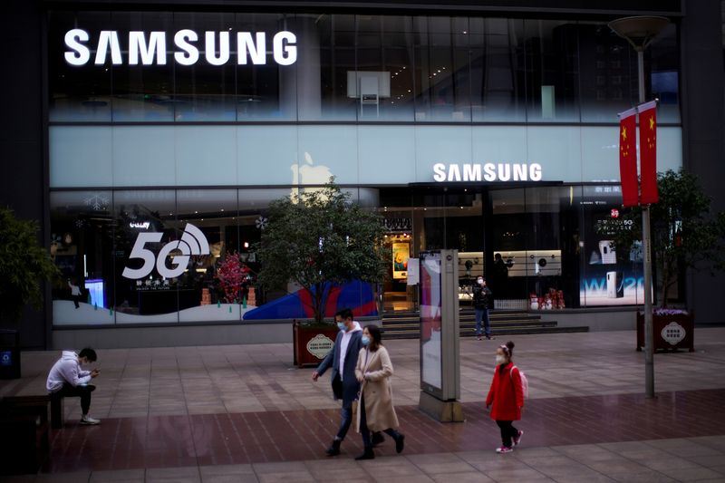 © Reuters. FILE PHOTO: People wears masks in front a Samsung Store at a main shopping area, in downtown Shanghai