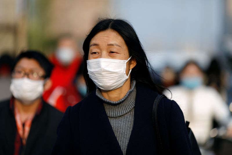 &copy; Reuters. Pessoas com máscara de proteção caminham pelas ruas de Pequim