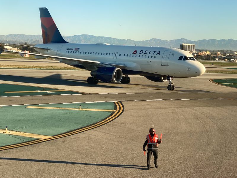 &copy; Reuters. An airport worker guides a Delta Air Lines Airus A319 plane on the tarmac at LAX in Los Angeles