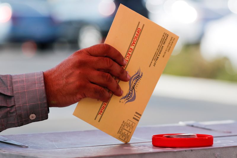 &copy; Reuters. FILE PHOTO: An election worker places a mail-in ballot into an election box at a drive-through drop off location at the Registrar of Voters in San Diego, California