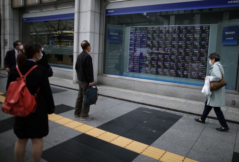 &copy; Reuters. People wearing protective face masks look at a stock quotation board outside a brokerage in Tokyo