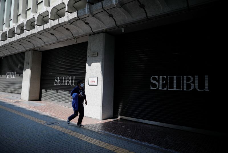 &copy; Reuters. A passerby wearing a protective face mask, following an outbreak of the coronavirus disease, walks past in front of temporary closed Seibu department store in Tokyo
