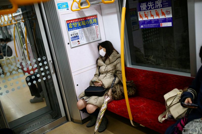 © Reuters. A woman wearing a protective face mask, following an outbreak of the coronavirus disease (COVID-19), rests as she travels inside a train in Tokyo