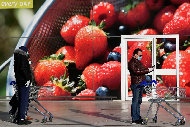 &copy; Reuters. FOTO DE ARCHIVO: Compradores con máscaras faciales de protección hacen cola frente a un supermercado Tesco mientras siguen las reglas de distanciamiento social en el oeste de Londres mientras la propagación de la enfermedad coronavirus (COVID-19) conti