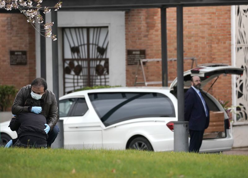 &copy; Reuters. Familiares perto de caixão de pessoa que morreu de coronavírus em crematório de Madri