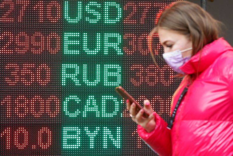 © Reuters. FOTO DE ARCHIVO: Una mujer pasa junto a un tablero que muestra los tipos de cambio en Kiev