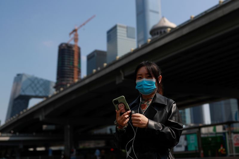 &copy; Reuters. Una mujer usa su smartphone mientras camina por el Distrito Central de Negocios de Pekín en China, 17 de abril de 2020