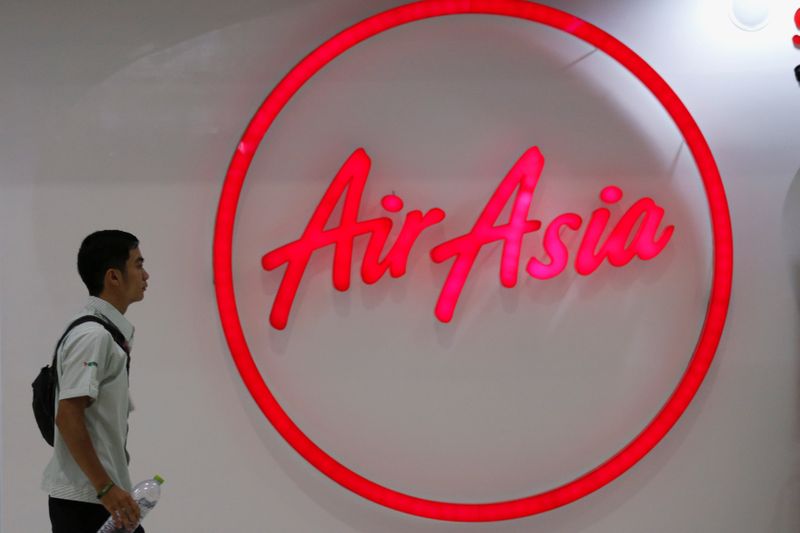 &copy; Reuters. A man walks past the logo of AirAsia at Don Muang International Airport in Bangkok