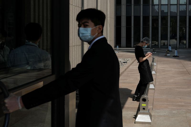 © Reuters. Chineses com máscara de proteção caminham pelo distrito financeiro de Pequim