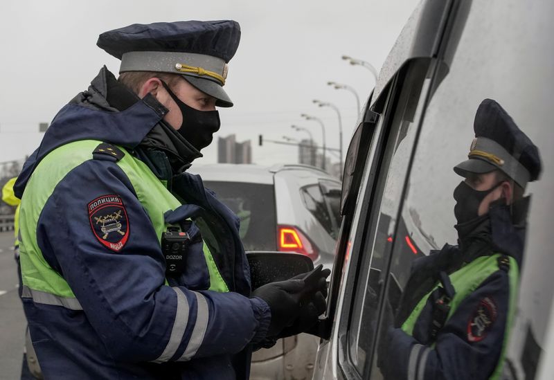 &copy; Reuters. A traffic police officer wearing a protective mask uses a mobile device while checking a pass to travel, at a checkpoint set up after Moscow authorities tightened up measures to prevent the spread of the coronavirus disease (COVID-19), in Moscow