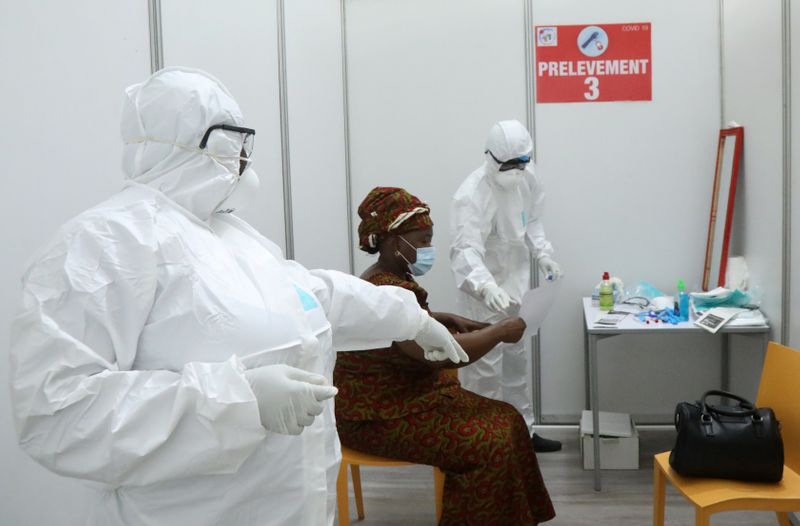 &copy; Reuters. Un miembro del personal médico con equipo de protección da un documento a una mujer después de tomar un frotis,  durante la propagación de la enfermedad del coronavirus (COVID-19), en Abidjan,