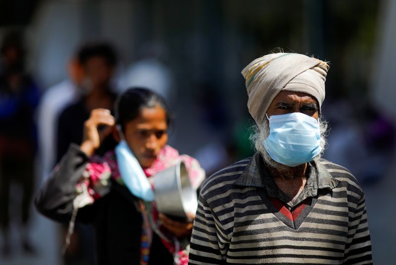 &copy; Reuters. Indianos com máscaras de proteção caminham pelas ruas de Nova Délhi durante quarentena imposta pelo governo