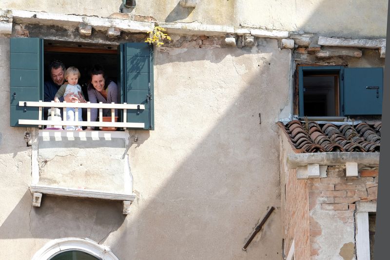 &copy; Reuters. Família olha pela janela de apartamento em Veneza durante quarentena do coronavírus