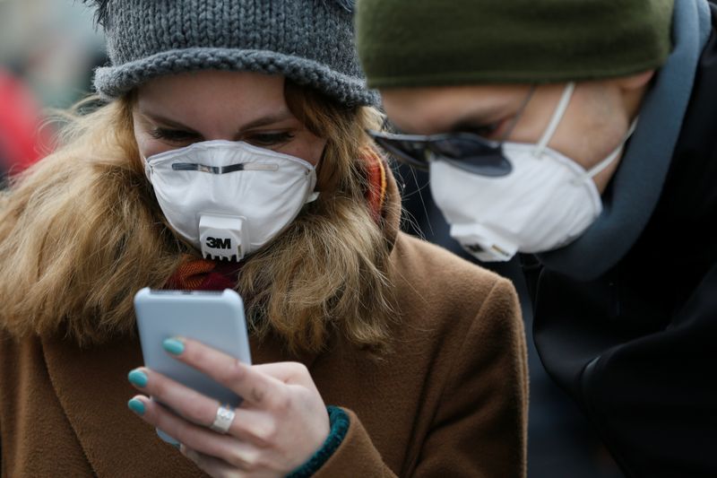 © Reuters. Com máscara de proteção contra coronavírus, mulher utiliza celular em Kiev, Ucrânia