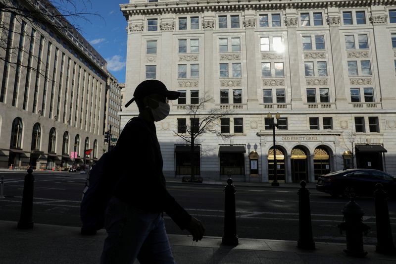 © Reuters. Una persona con una máscara camina por una calle casi vacía en el brote de coronavirus cerca del Departamento del Tesoro en Washington