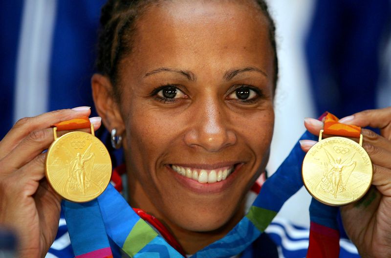 &copy; Reuters. FILE PHOTO: Kelly Holmes, Olympic champion over 800m and 1500m, displays her two gold medals minutes after her a..