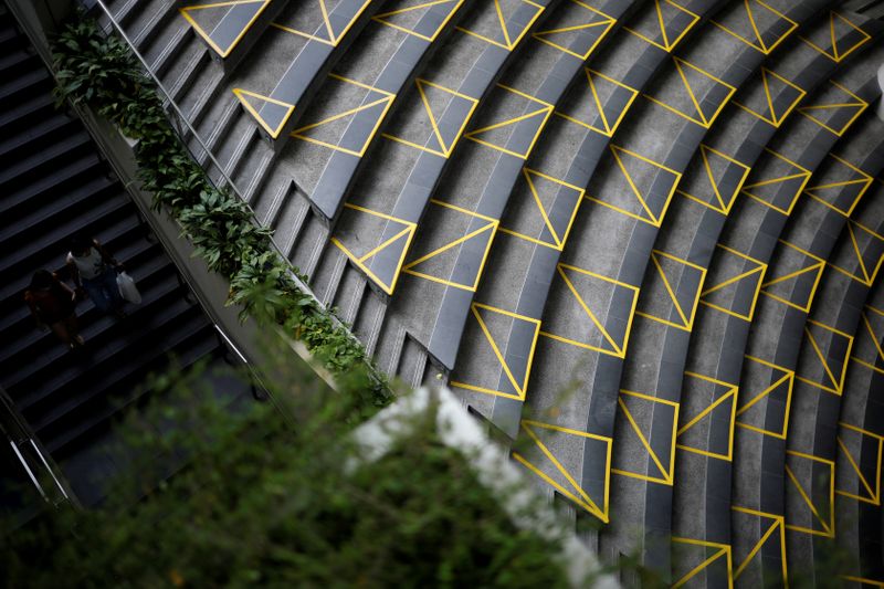 &copy; Reuters. FILE PHOTO: People pass a public seating area marked with yellow tape to encourage social distancing, during the coronavirus outbreak (COVID-19), at a mall in Singapore
