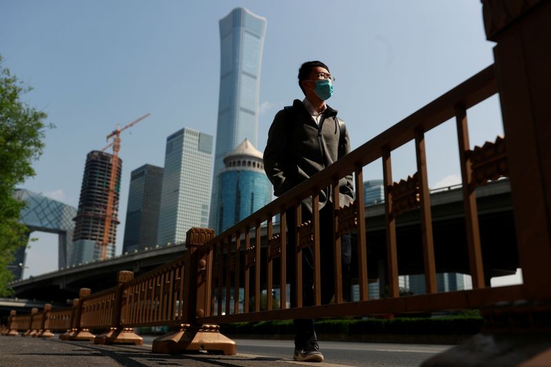 &copy; Reuters. Прохожий в маске на фоне делового центра Пекина