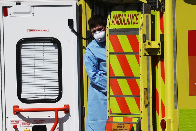 &copy; Reuters. Agente de saúde britânico com roupa de proteção aguarda paciente em ambulância