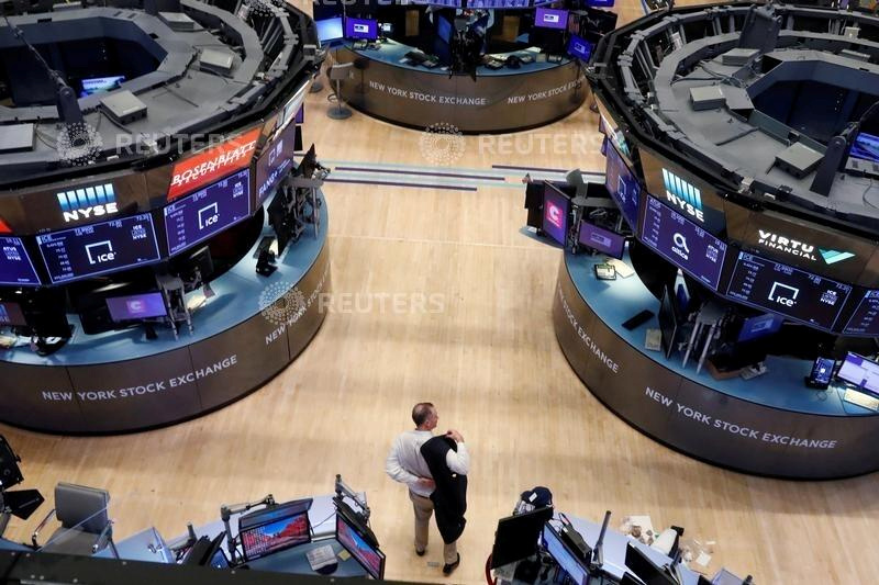 © Reuters. FILE PHOTO: A trader puts on his jacket on the floor of the New York Stock Exchange (NYSE) as the building prepares to close indefinitely due to the coronavirus disease (COVID-19) outbreak in New York