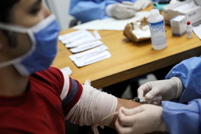 &copy; Reuters. FILE PHOTO: Medical workers take blood samples from a man for a coronavirus disease (COVID-19) rapid test at a medical facility due to the COVID-19 outbreak in Caracas