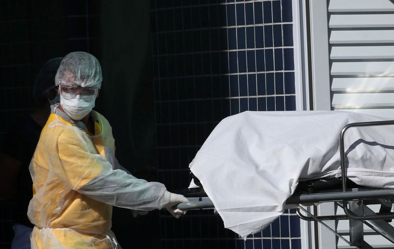 © Reuters. Profissional de saúde com roupa de proteção remove corpo para caminhão refrigerado em hospital do Rio de Janeiro