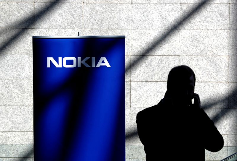 &copy; Reuters. A man uses his mobile phone near a banner displaying a Nokia logo during the Mobile World Congress in Barcelona
