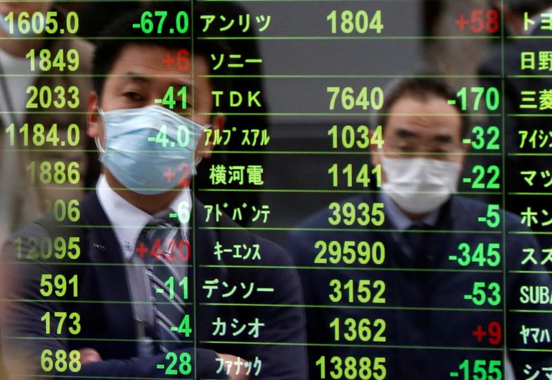 &copy; Reuters. Due uomini con mascherine riflesse su uno schermo con informazioni sulla Borsa di Tokyo