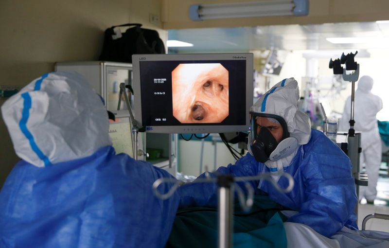 &copy; Reuters. Profissionais de saúde com roupa de proteção tratam paciente com Covid-19 em hospital de Moscou