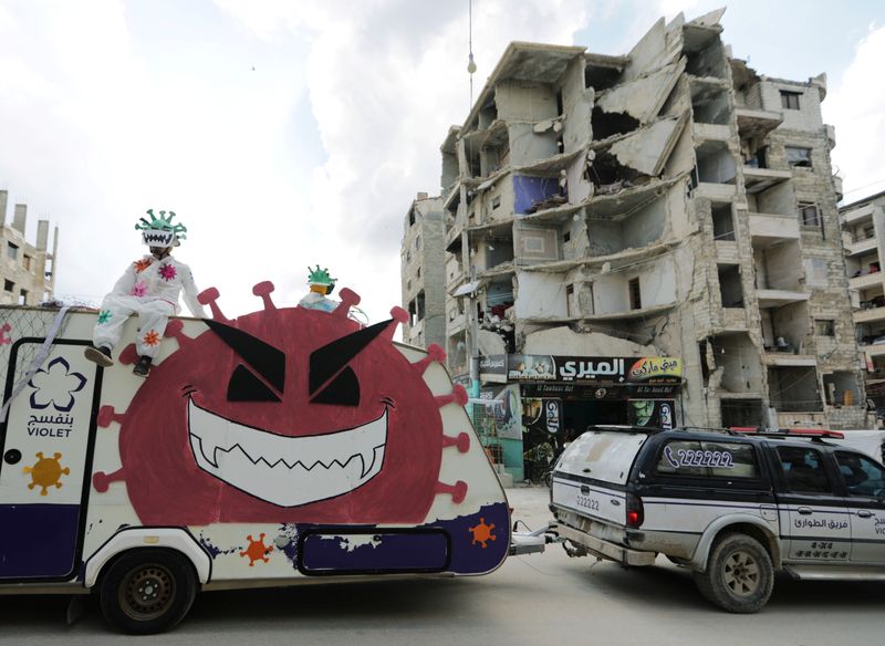 © Reuters. Volunteers dressed in coronavirus-themed costumes stand on a vehicle during a campaign organised by the Violet Organization in the rebel-held Idlib city