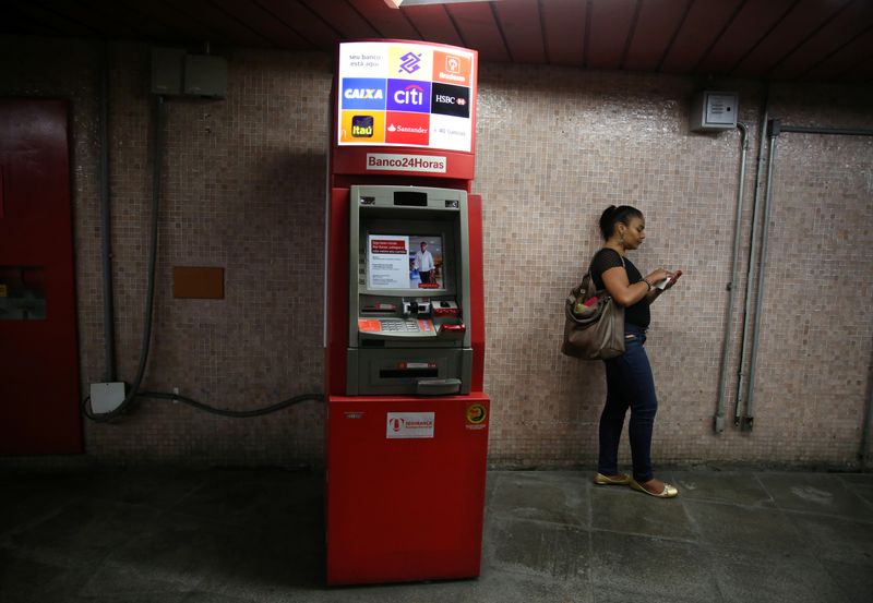 © Reuters. Mulher utiliza celular ao lado de caixa eletrônico no Rio de Janeiro (RJ)