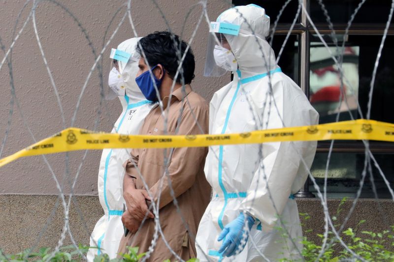 &copy; Reuters. Police officers wearing protective suits pick up an illegal immigrant from an apartment under enhanced lockdown, during the movement control order due to the outbreak of the coronavirus disease (COVID-19), in Kuala Lumpur