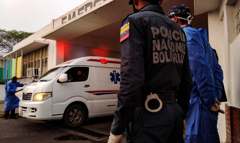 &copy; Reuters. Trabajadores de la salud y miembros de la Policía Nacional Bolivariana observan cómo llega una ambulancia con prisioneros fuera de un hospital, después de que estalló un motín dentro de una prisión en Guanare, Venezuela.