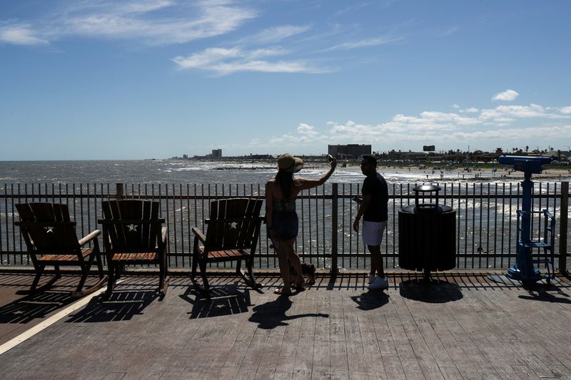 © Reuters. Couple take photographs from pier after partial-reopening of economy during coronavirus disease pandemic in Galveston, Texas