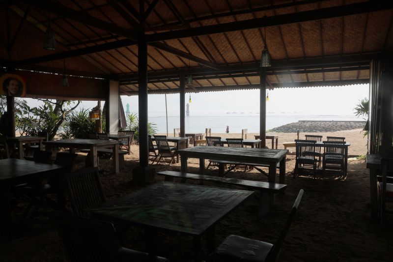 &copy; Reuters. An empty restaurant is pictured with a tourist walking in the background, amid the spread of coronavirus disease (COVID-19) outbreak, at Sanur beach in Bali