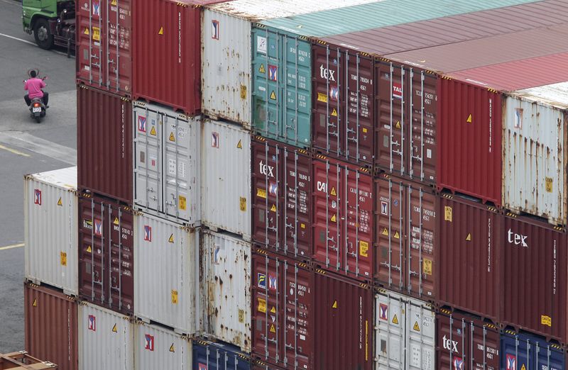 © Reuters. A man rides a scooter near containers at Keelung port