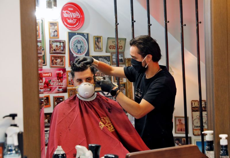 &copy; Reuters. Un peluquero con una máscara protectora y guantes corta el pelo de un cliente en una peluquería en el primer día de la flexibilización del confinamiento contra la propagación de la enfermedad de coronavirus (COVID-19), en Salónica, Grecia