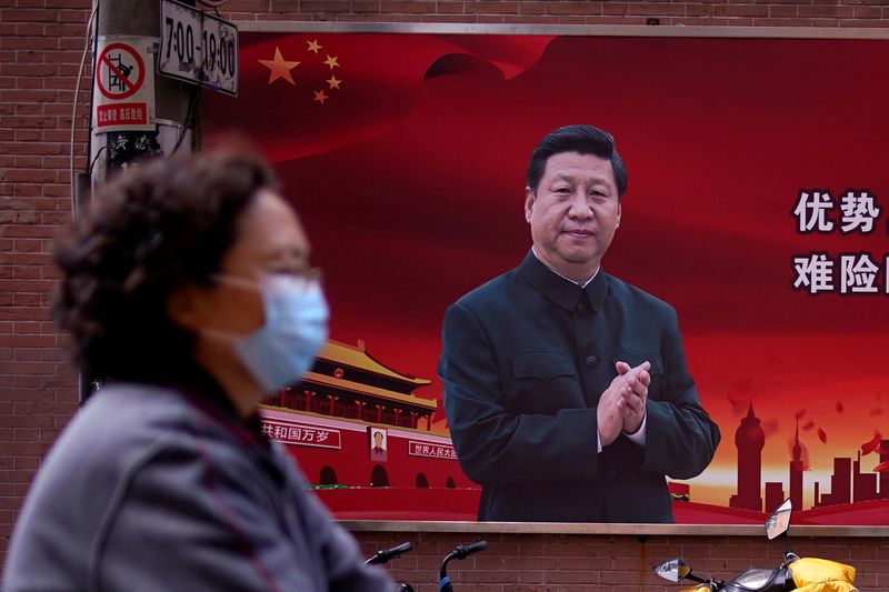 © Reuters. FILE PHOTO: Woman is seen past a portrait of Chinese President Xi in Shanghai