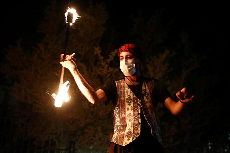 &copy; Reuters. Un intérprete juega con fuego durante el Ramadán en una calle en Jerusalén Oriental para entretener a las personas con restricciones por la pandemia del coronavirus.